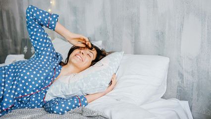 Cute happy woman relaxing home dressed in blue dots pyjamas