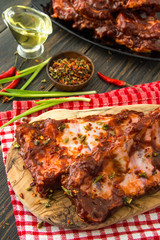 Flavored bbq spareribs with red peppers, green onion and olive oil on a craft wooden cutting board