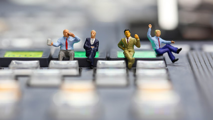 Obraz premium Miniature people : businessman sitting on switcher control of Television Broadcast,color buttons