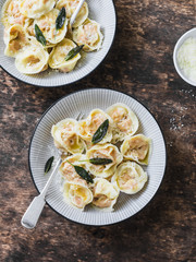 Pumpkin ravioli with sage butter and parmesan cheese on wooden background, top view. Delicious vegetarian, seasonal comfort food