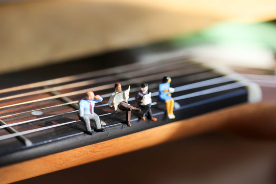 Miniature people : Businessman sitting on acoustic guitar. time of relax or music relax concept.