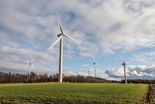 A panorama view over wind farm landscape in Germany with white generator turbines