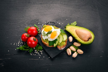 Avocado sandwich with quail eggs, cucumber and pistachios. On a wooden background. Top view. Free space for your text.