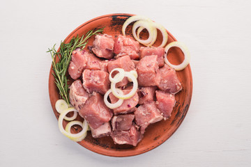 Raw uncooked meat sliced in cubes on wooden rustic background, top view.
