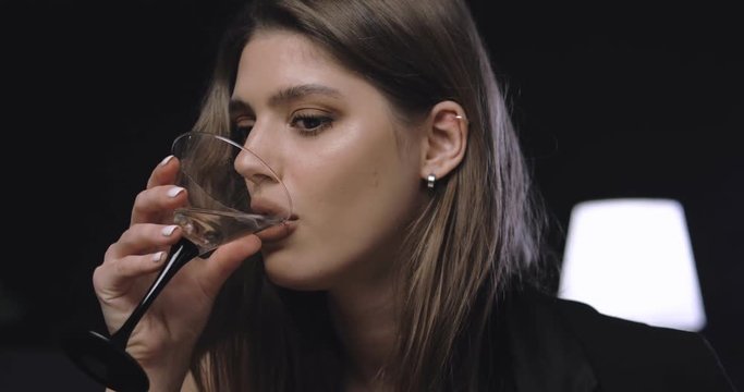 closeup portrait of pretty good looking girl with nice make up enjoying martini and eating olive, flirting with camera. romantic joyful evening
