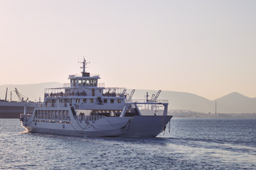 Fototapeta na wymiar A large white ferry floats away into the distance. Water trail. Greece.