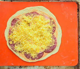 raw pizza with cheese and mushrooms on a red background
