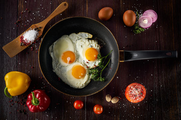 Pan of fried eggs on dark table surface, top view