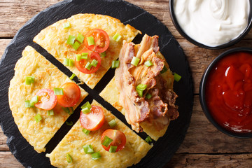 Potato Boxty with bacon, tomatoes, onions and sauce close-up. Horizontal top view