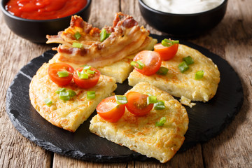 Delicious potato pancakes with bacon, tomatoes, onions and sauces close-up. horizontal
