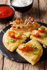 potato pancakes with bacon, tomatoes, onions and sauces close-up. vertical 