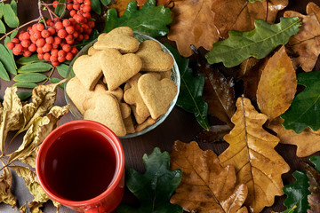 Autumn still life. Heart cookie. Black tea. Rowan branch. Different leaves