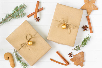 Christmas gift boxes on white background, wrapped with natural paper. Christmas decorations in the background, top view.