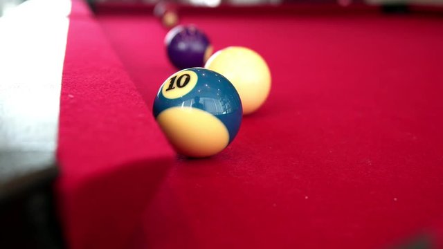 Playing the pool-billiard game on red baize table. This is sports.