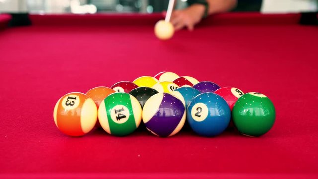 Playing the pool-billiard game on red baize table. This is sports.