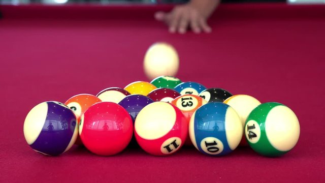 Playing the pool-billiard game on red baize table. This is sports.