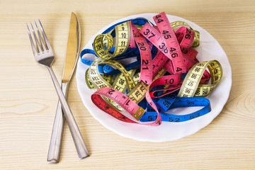plate with tape measures and fork and knife, concept of diet and slimming
