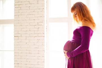 pregnant woman in purple dress in white room