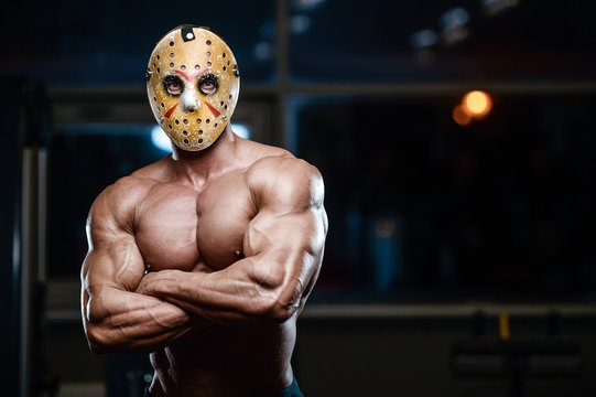 horror brutal mask man strong bodybuilder athletic fitness man in scary hockey mask in the gym