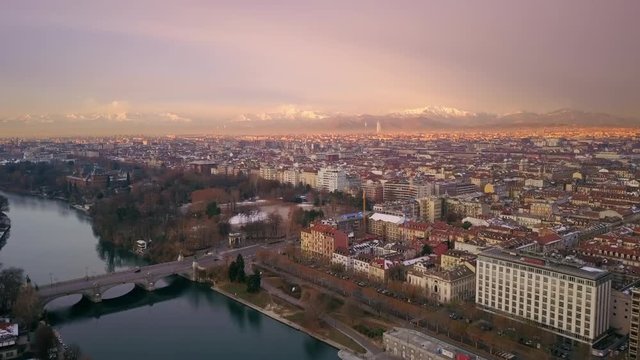 turin aerial shot flying over city at sunrise snow covered alps in the background