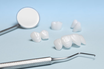 Dental tools and dentures on a light blue background - Ceramic veneers - lumineers