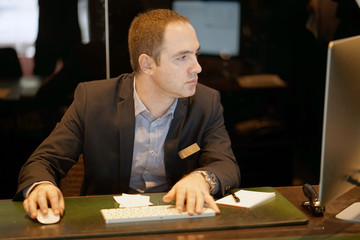 Hotel manager. A man-reception worker makes out an order for booking a room. Profile shot of...