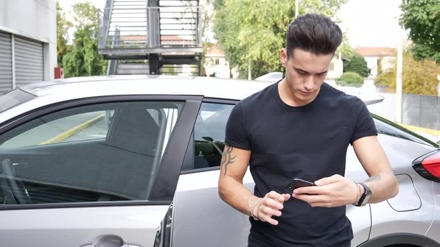 Close up Gorgeous Young Man Outside Car, Lost and Looking for Directions on Smartphone, Puzzled and Confused as to Where to Go