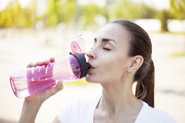 Fitness woman drinking water after jogging in the morning