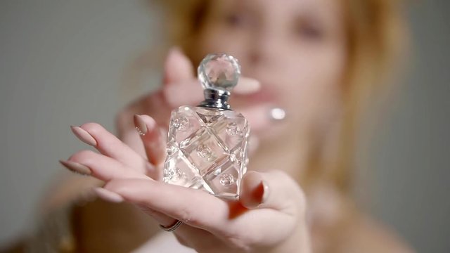 Close up shot of expansive perfume bottle in the hand of beautiful woman.