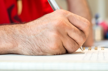 Close up of a student or businessman hand taking notes in his notebook with pen.