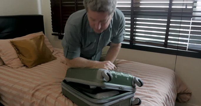 Tourist man having trouble fitting all his belongings in his suitcase