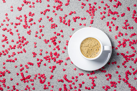 A cup of coffee, small red hearts over stone  on background. St. Valentine's day concept. Top view, copy space.