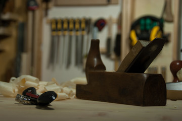 Old fashion wood plane on the workbench with other tools in the background.