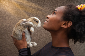 Idealistic young afro american woman daydreaming with Christmas bunny rabbit in her hands