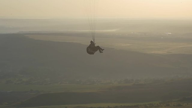 Paraglider in the harness climbs