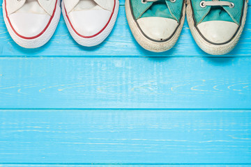 Top view of the a pair of new and old sneakers next to each other, the concept of transferring experience and changing generations, hipster shoes on a wooden background