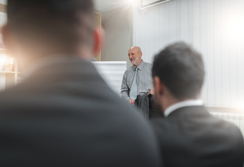 Group of business workers solving financial problems with the use of graphs and coefficients.Senior business man holds lectures.