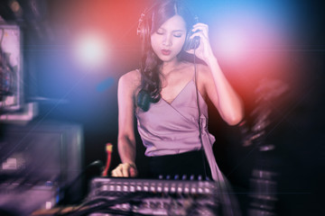 Woman DJ party concept. Young Chinese woman DJ mixing music on colorful background listening to her...