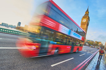 Big Ben daytime and red double decker bus blurred with his movement