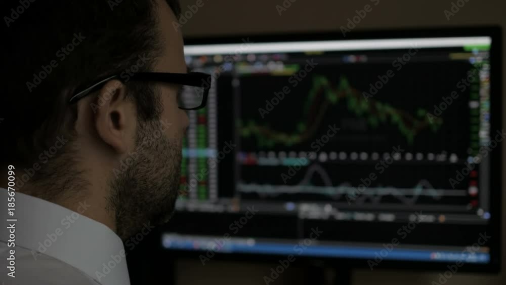 Wall mural businessman sitting and using computer showing trading graph stock exchange trading graph screen bac