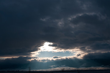 Obraz premium Fast moving snow clouds in December , sunlights breaking through the hole.