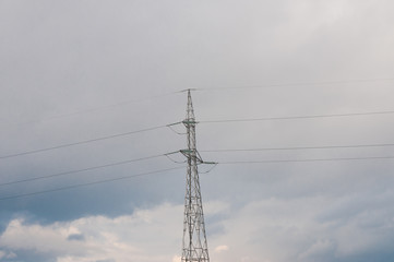 Electricity pylon on cold winter day, cloudy background with some blue sky.