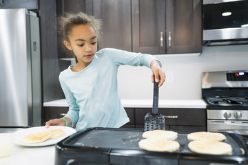 Girl making pancakes in domestic kitchen 