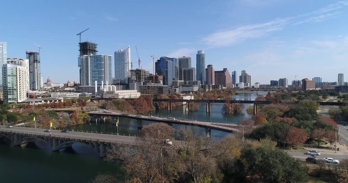 A slow rising aerial establishing shot (DX) of the Austin city skyline with the Pfluger Pedestrian Bridge and Lamar Boulevard Bridge in the foreground on a late sunny Autumn day.  	