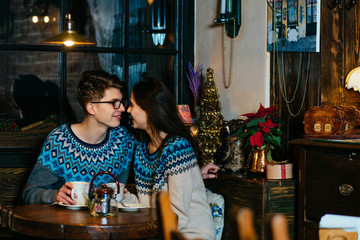 Cute couple drinking tea in cafe in winter time.