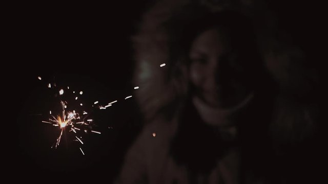  bright burning bengal light stick. Young adult woman hold sparkler in hand and admire flame, slow motion portrait shot