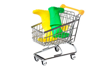 Metal shopping basket on wheels with yellow handle with two pairs of toy yellow and green rubber fun boots  inside isolated on white background, consumer basket, food cart, front and side view.