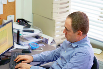 Fototapeta na wymiar Man Working At Desk In Busy Creative Office. Office worker man at the computer.
