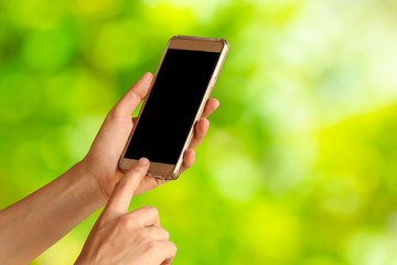 woman hand hold and touch screen smart phone,tablet,cellphone on green nature background