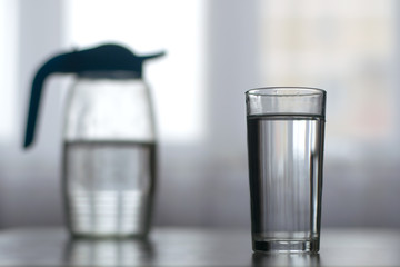 a glass filled with water and a decanter in the background